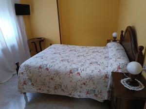a bedroom with a bed with a floral bedspread at PENSIÓN* AS VIÑAS in Puebla del Brollón