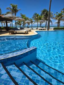 a swimming pool with palm trees on the beach at Hotel Rede Beach in Trairi