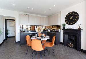 a kitchen with a table and chairs and a clock at 4 Beds 2 Bath Stunning Apartment On Street Parking in Brighton & Hove