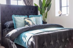a black bed with blue pillows on top of it at 4 Beds 2 Bath Stunning Apartment On Street Parking in Brighton & Hove