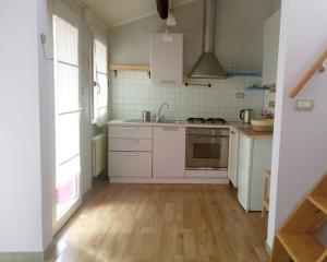 cocina con electrodomésticos blancos y suelo de madera en La Casina di Chiara, en Rávena