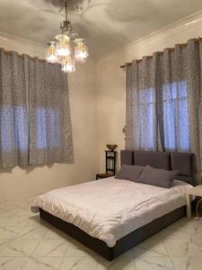 a bedroom with a bed with blue curtains and a chandelier at Marhaba,welcom. in Fès