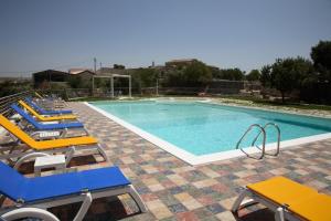 a swimming pool with blue and yellow chairs next to it at Casato Licitra in Donnafugata