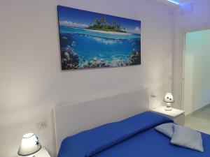 una camera con un letto blu e un dipinto sul muro di SoleMare Rooms "Acquamarina" a Procida