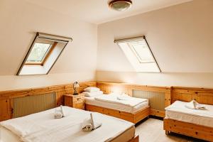 two beds in a room with two windows at Kakukk Vendéglő Panzió in Bánd