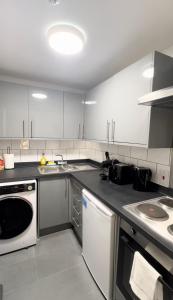a kitchen with white cabinets and a white dishwasher at Stylish studio on Edgware Road (Marylebone) in London