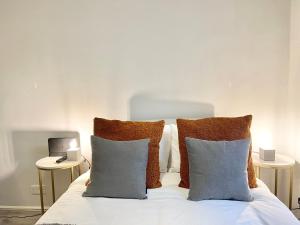 a bed with white sheets and pillows with two tables at Stylish studio on Edgware Road (Marylebone) in London