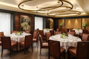 a restaurant with tables and chairs and a large chandelier at The Beaumont Mayfair in London