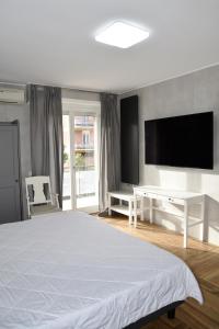 1 dormitorio con 1 cama blanca y TV de pantalla plana en La Maison Latina Guest House, en Latina