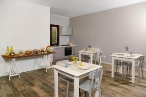 una cucina con tavoli e sedie bianchi in una stanza di B&B Vignicella a Castelbuono