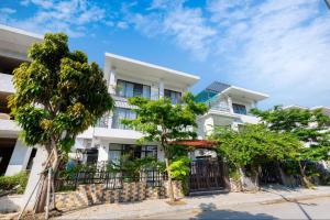 un edificio blanco con árboles delante de él en Hệ Thống Sen Biển Hotel FLC Sầm Sơn - Restaurant Luxury, en Sầm Sơn