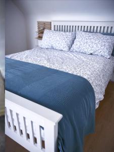 a white bed with a blue comforter and pillows at The Gate House, Kilmullen in Portarlington