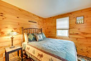 una camera da letto con pareti in legno, un letto e una lampada di Rustic Cabin Apartment in Lake George, NY a Lake George
