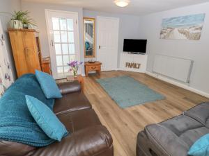 a living room with a brown leather couch and blue pillows at Willow Cottage in Ventnor