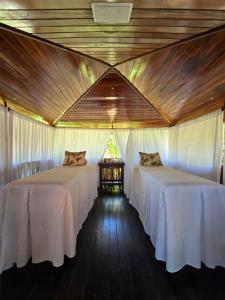two beds in a room with wooden ceilings at Hotel Rede Beach in Trairi