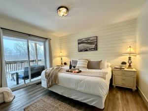 een slaapkamer met een groot bed en een balkon bij Beautiful tranquil centrally located condo in Collingwood
