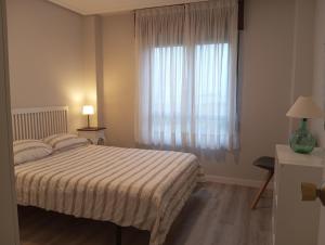 1 dormitorio con cama y ventana grande en apartamento Somo, en Somo