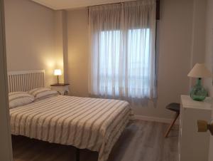 a bedroom with a bed and a large window at apartamento Somo in Somo