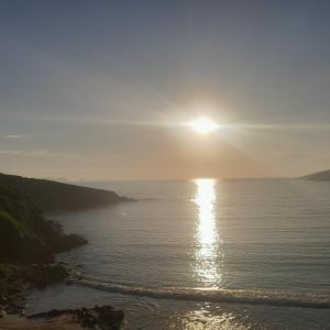 una puesta de sol sobre el océano con una playa en Hospedagem Pé Na Areia en Arraial do Cabo