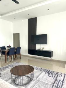 sala de estar con mesa y TV en la pared en Homestay Taman Melati Jerantut, en Jerantut