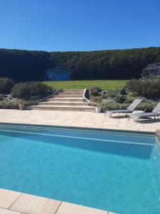 una piscina con sillas y una casa en el fondo en Le Gîte De Roseraie, en Brécé