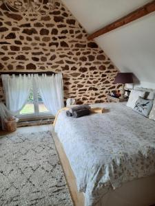 1 dormitorio con 1 cama grande y pared de piedra en Le Gîte De Roseraie, en Brécé