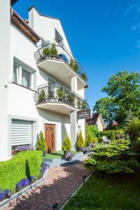 een wit gebouw met een balkon en een tuin bij Willa Morski Klimat in Łeba