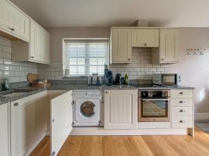 eine Küche mit weißen Schränken, einer Waschmaschine und einem Trockner in der Unterkunft Sancreed House Cottages in Penzance