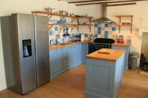 een keuken met blauwe kasten en een roestvrijstalen koelkast bij Cha16 - Nanteuil En Vallee - Touchbaudrand in Messeux