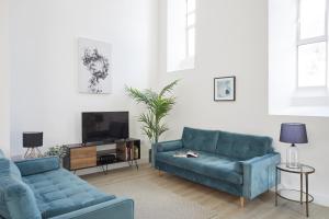 a living room with two blue couches and a tv at No 5 Old Church in Ventnor