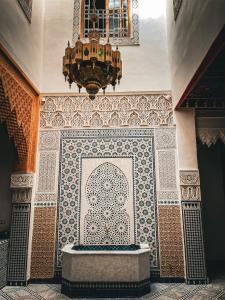 Habitación con pared de baldosa y lámpara de araña. en Riad Rasia en Fez