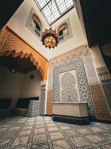 Habitación con lámpara de araña y suelo de baldosa. en Riad Rasia en Fez