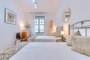 a white bedroom with two beds and a mirror at Acogedor y Elegante Apartamento en Irala in Bilbao