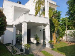 a white house with palm trees in front of it at Vidushi Home in Minuwangoda