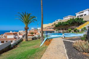 a resort with a swimming pool and a palm tree at Ocean View Apartment Montesol I in Adeje