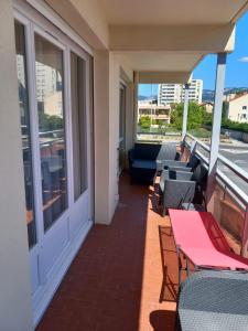Un balcón con mesas y sillas en un edificio en Appartement 1er étage, 66 m² en La Seyne-sur-Mer
