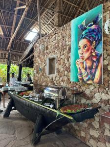 a table of food with a painting of a woman at Kiwengwa Bungalow Boutique Resort in Kiwengwa