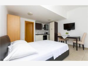 Cet appartement comprend une chambre avec un grand lit blanc et une cuisine. dans l'établissement Apartmani Livajić, à Duće