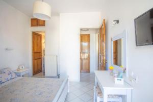 a white bedroom with a bed and a table at A1- Mikro Karavi Apartment in Nydri
