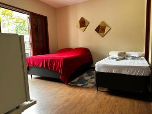 a bedroom with two beds and a red blanket at Village Hostel in Petrópolis