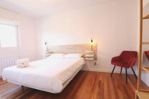 - une chambre avec un grand lit blanc et une chaise rouge dans l'établissement Notel Club - Oasis urbano en Santander, à Santander