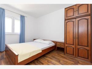 Schlafzimmer mit einem Bett und einem Holzschrank in der Unterkunft Apartmani Livajić in Duće