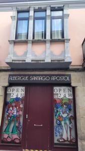 un edificio con una puerta roja y ventanas en Albergue Santiago Apostol, en Logroño