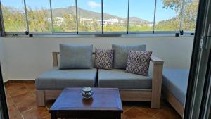 ein Sofa im Wohnzimmer mit Fenstern in der Unterkunft Best Apartment La Cassia Beach & Golf Resort, Cabo Negro in Cabo Negro