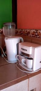a counter with two coffee cups and a toaster on it at Cabañas Zunzun in San Ramón