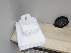 ein Haufen Handtücher auf einem Tisch neben einer Uhr in der Unterkunft Hanepoot 503 in Paarl