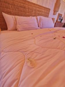 Mhamid Luxury Camp في Mhamid: سرير أبيض كبير مع ملاءات ووسائد بيضاء