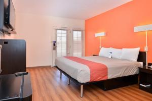 Days Inn by Wyndham Brawley في Brawley: غرفة نوم بسرير كبير بجدار برتقالي