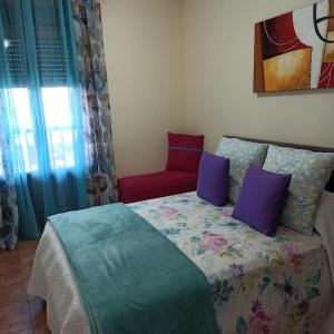 a bedroom with a bed with purple pillows and a red chair at La Colina Playa&Golf in Huelva