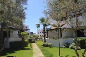 un jardin en face d'un bâtiment avec des palmiers dans l'établissement Best Apartment La Cassia Beach & Golf Resort, Cabo Negro, à Cabo Negro